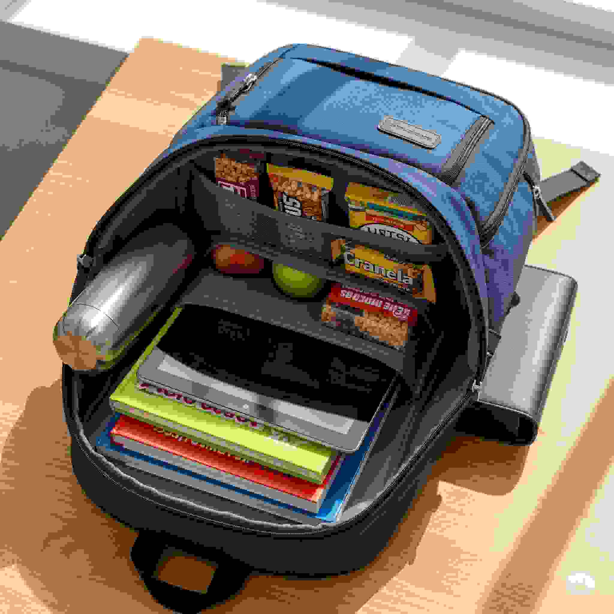 A well-organized backpack with books, a tablet, water bottle, and snacks, ready for a study trip.